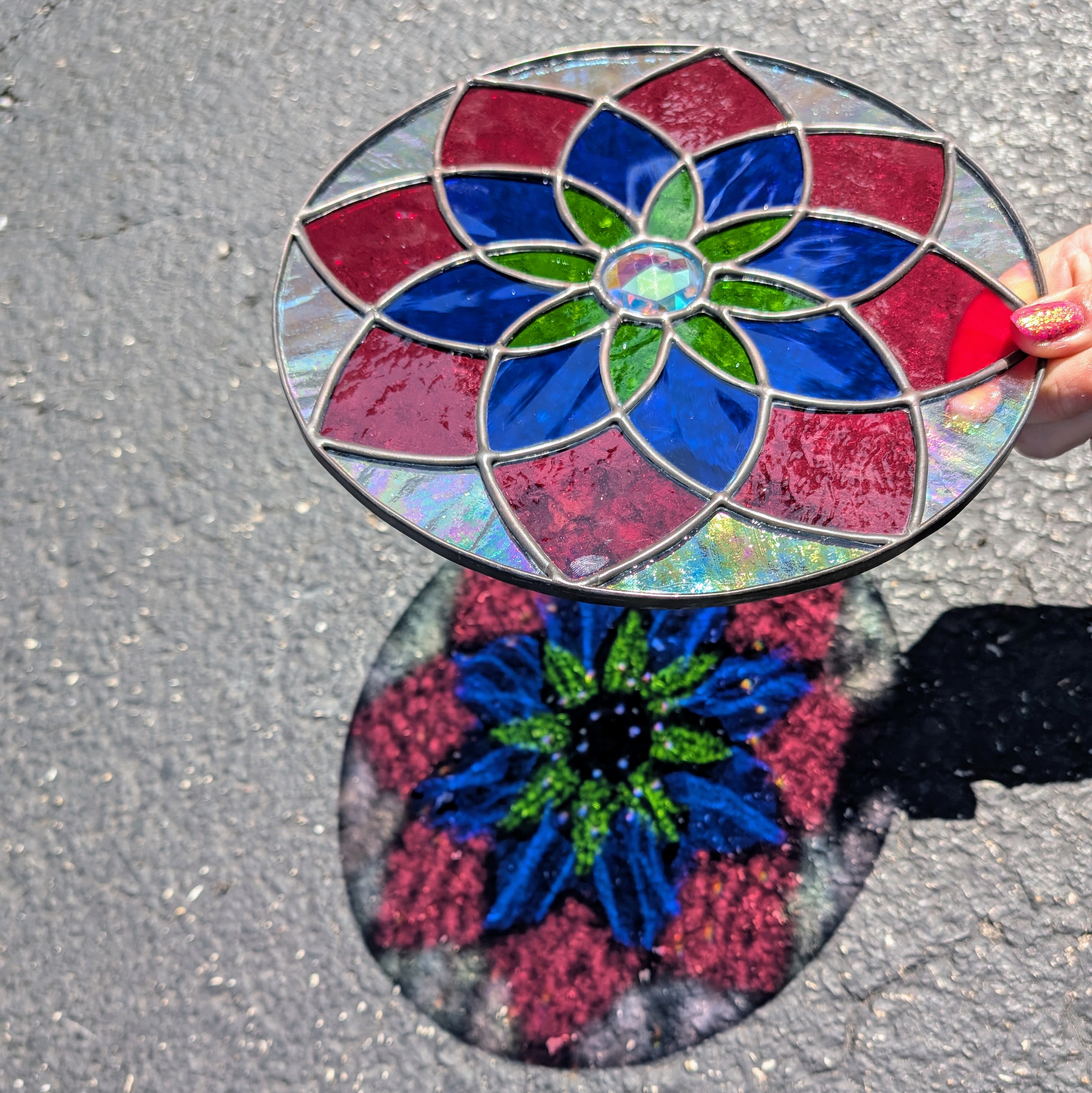 A circular stained glass mandala with pink, blue, and green