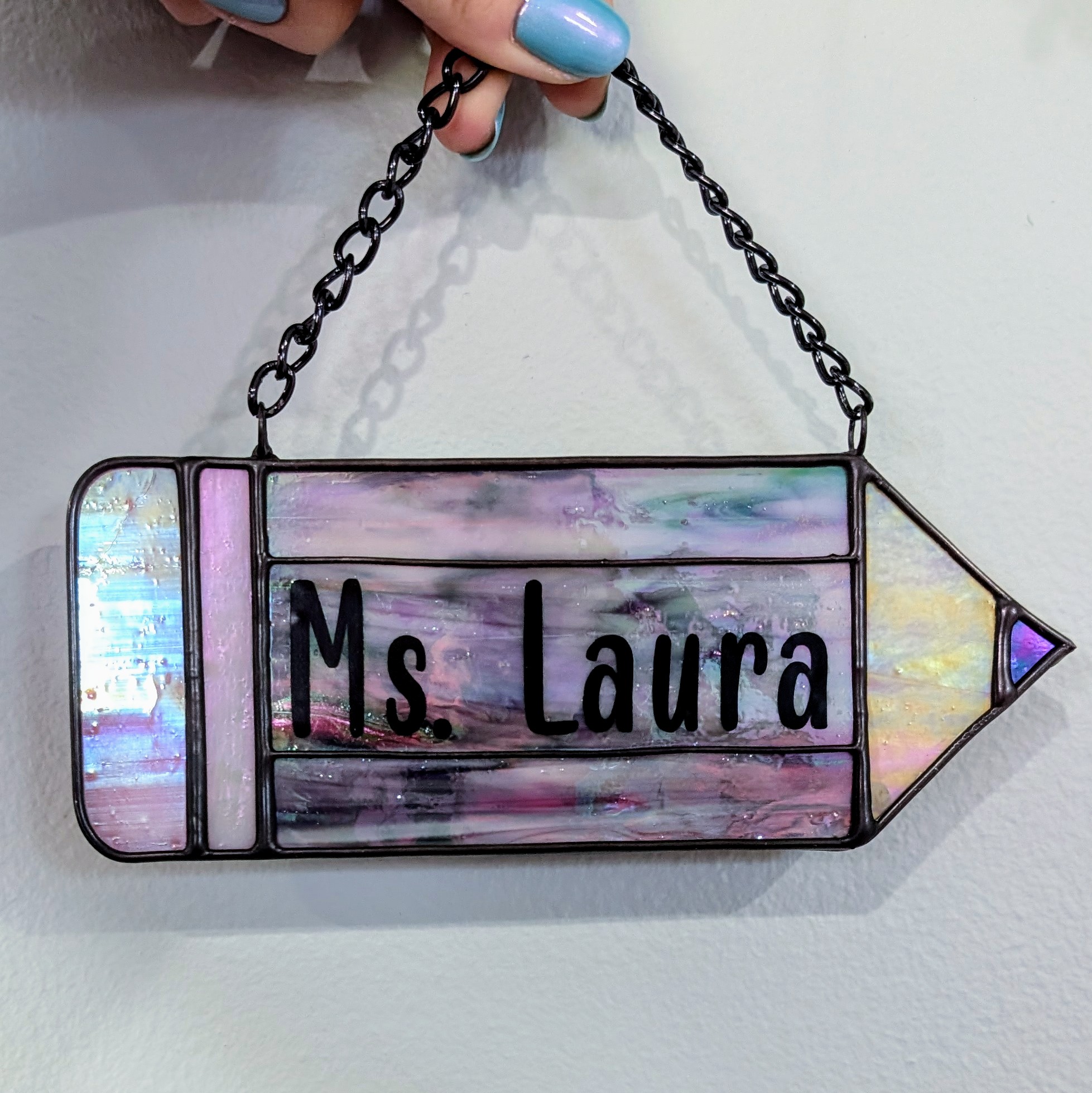 A purple stained glass pencil that reads 'Ms. Laura'