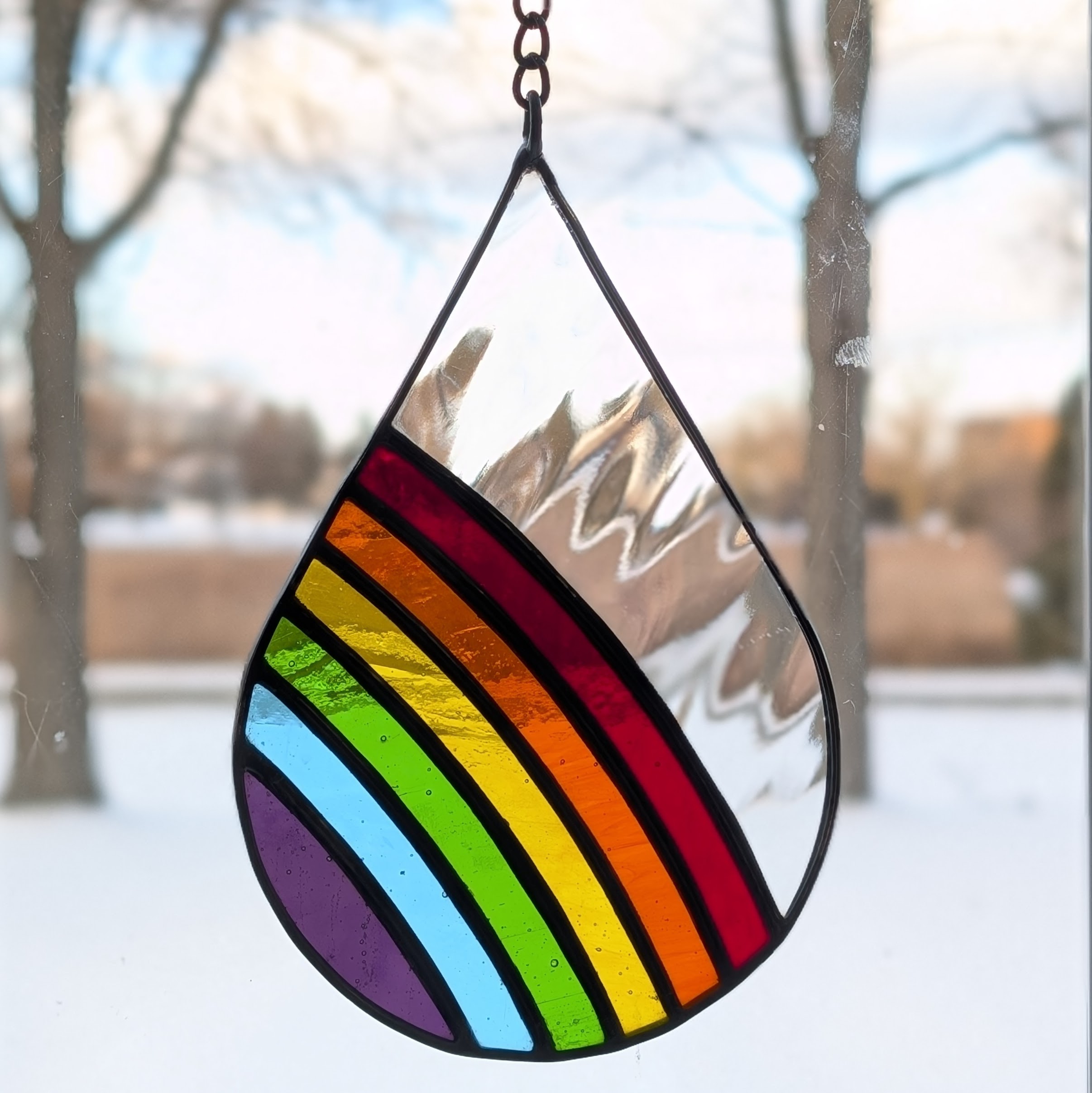 A stained glass raindrop with a rainbow in it